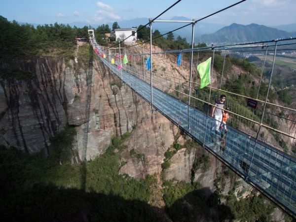 Uma ponte de vidro construda sobre um desfiladeiro a uma altura de 180 metros entre montanhas de Shinuizhai, na China, foi fechada nesta semana aps rachaduras aparecerem no local enquanto dezenas de turistas andavam na estrutura recm-reformada