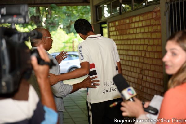 Holiver Guilherme, que estava no banco do passageiro, evita falar com a imprensa ao deixar a delegacia aps depoimento