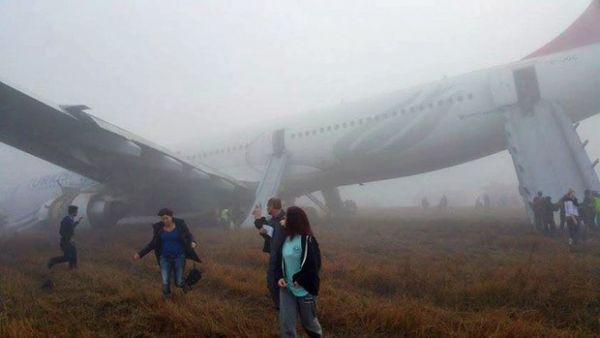 Passageiros deixam avio da Turkish Airlines que parou com o nariz na pista ao derrapar no pouso no aeroporto de Catmandu, Nepal
