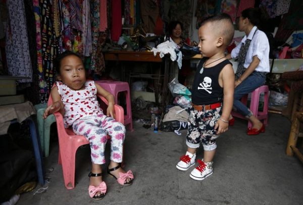 Zhang Huimin, de 17 anos ( esquerda),  vista ao lado de menino. Ela sofre de uma doena gentica que afetou seu crescimento (