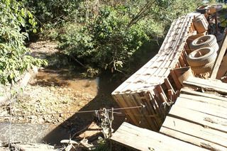 Ponte de madeira no suporta peso e caminho cai em crrego no Estado